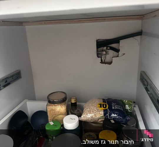 צינור גז חשוף בארון מטבח עם מוצרי מזון